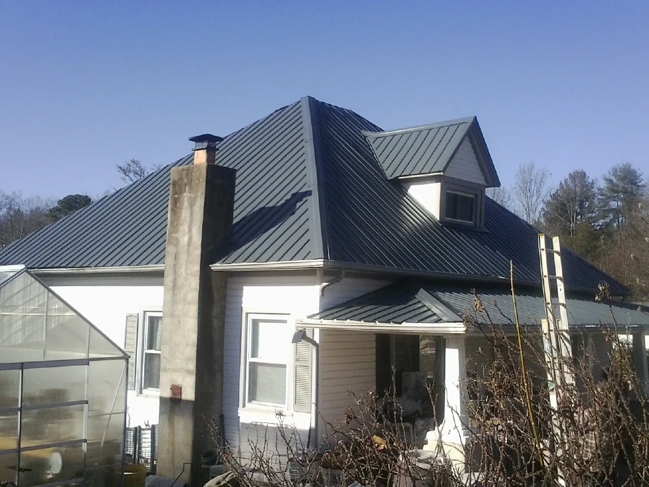 Dark blue standing seam metal roof on a white farmhouse with dormer — Slate & Tile Roof Repair by Roofing Brothers in New Cambria