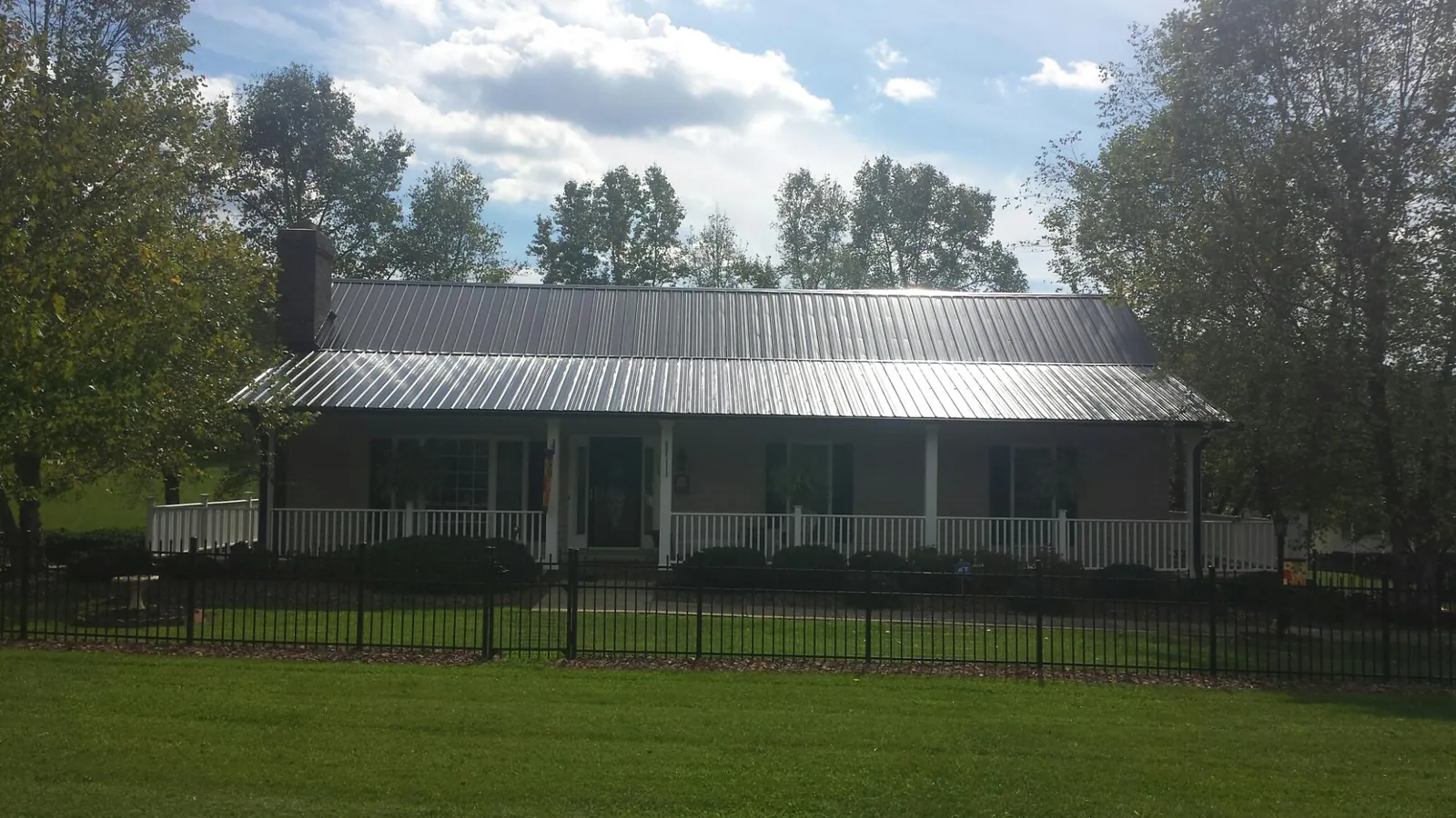 Gray metal roof on a brick ranch with a full width front porch — Gutter Guard Installation work by our crew in New Cambria