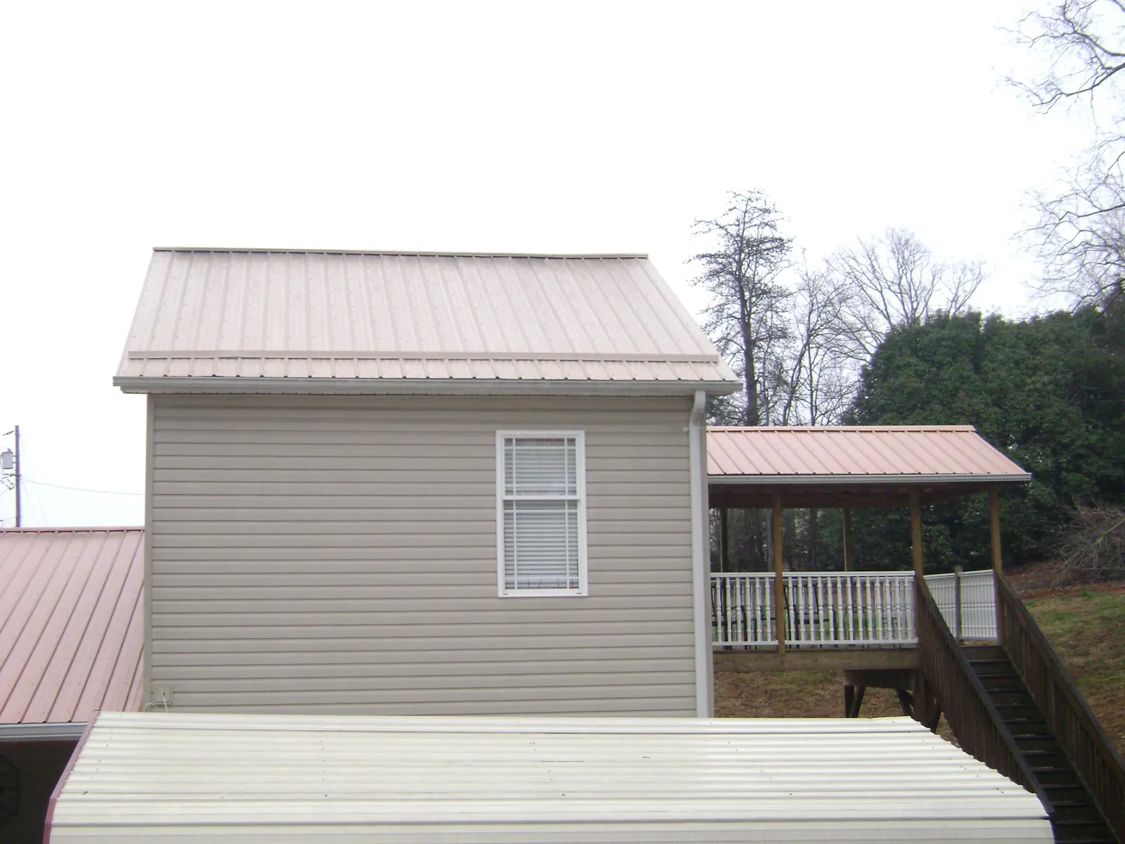 Tan metal roofs on a two story addition and attached porch, from a Roof Replacement job in New Cambria