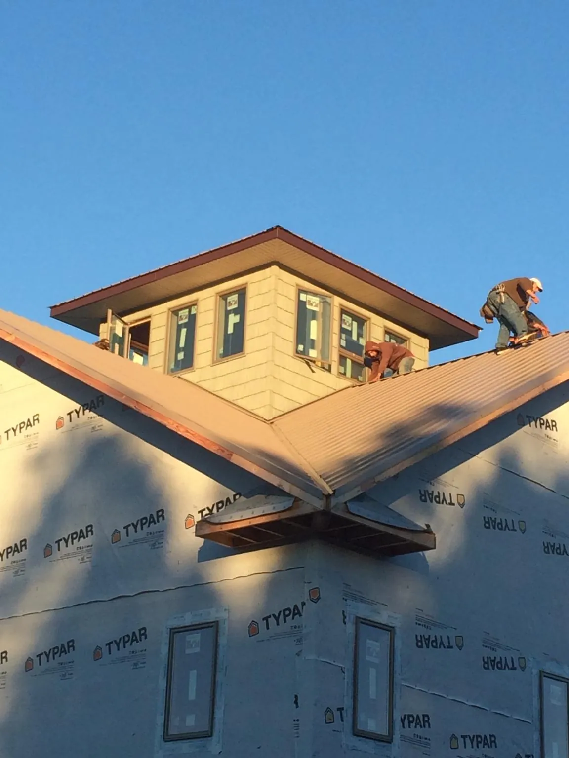 Roofers working around a rooftop cupola on a new metal roof at sunset — Roof Waterproofing in New Cambria by Roofing Brothers